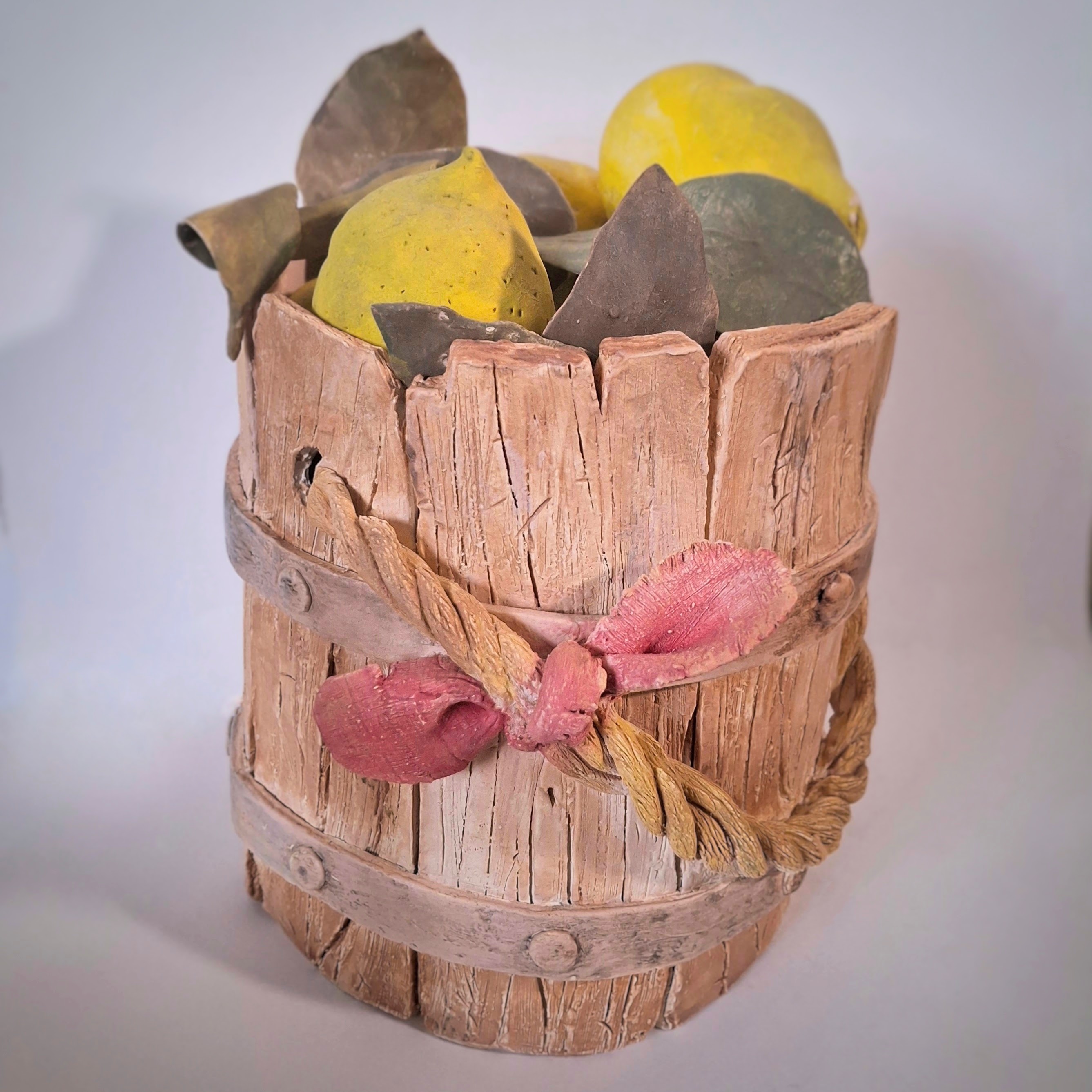 A ceramic sculpture of a wooden pail filled with lemons.