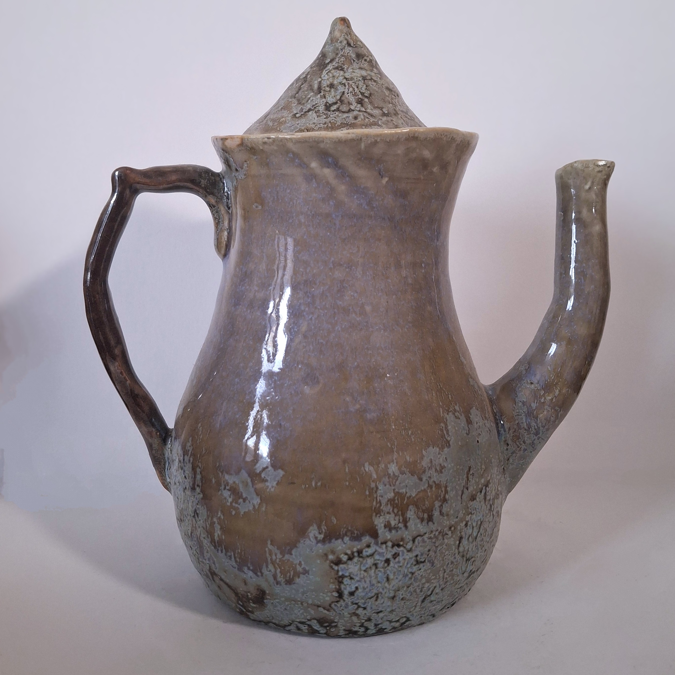 A tall, purple, ceramic teapot with a pointed lid.