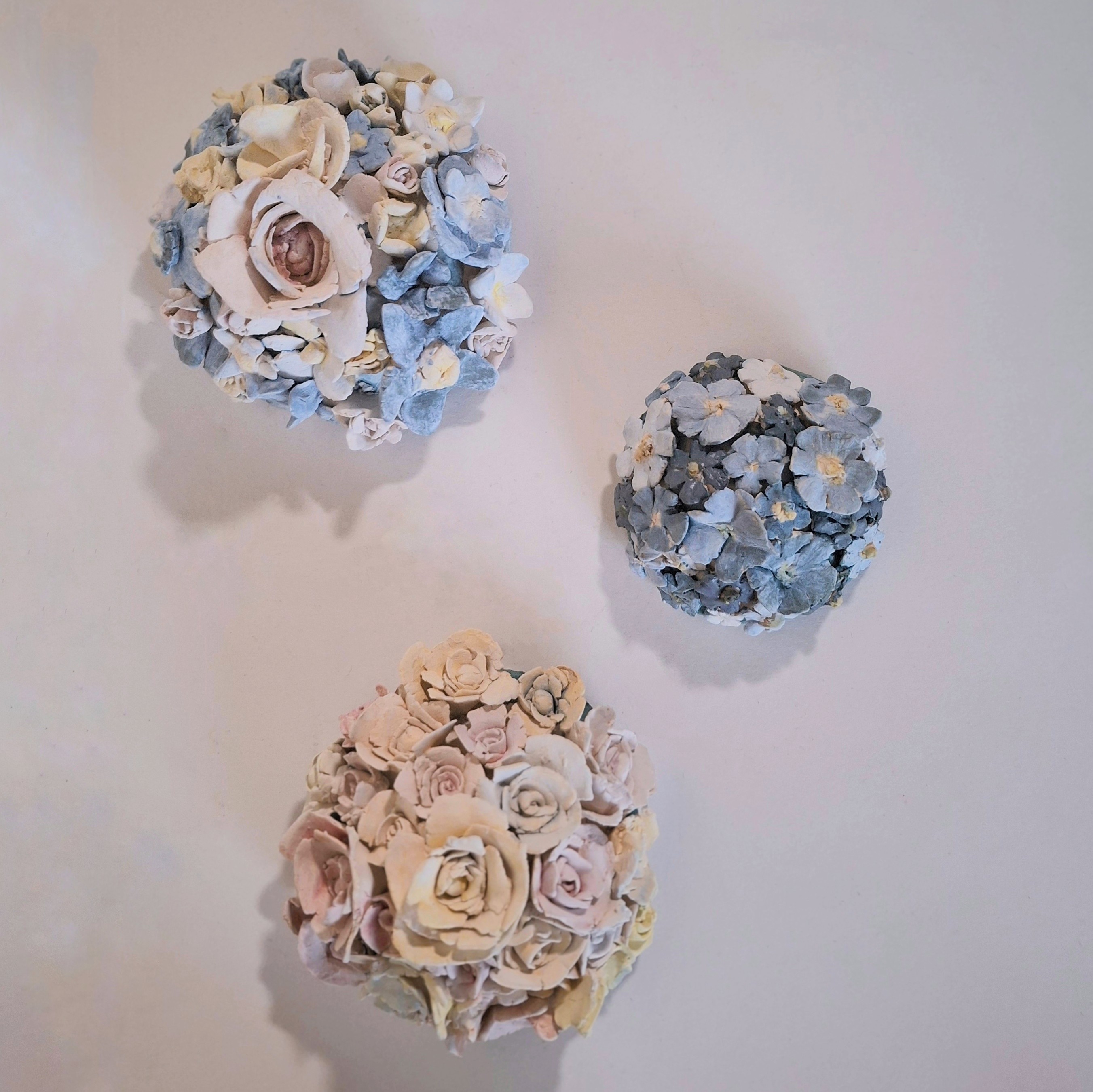 3 small circular ceramic sculptures of flowers bunches.