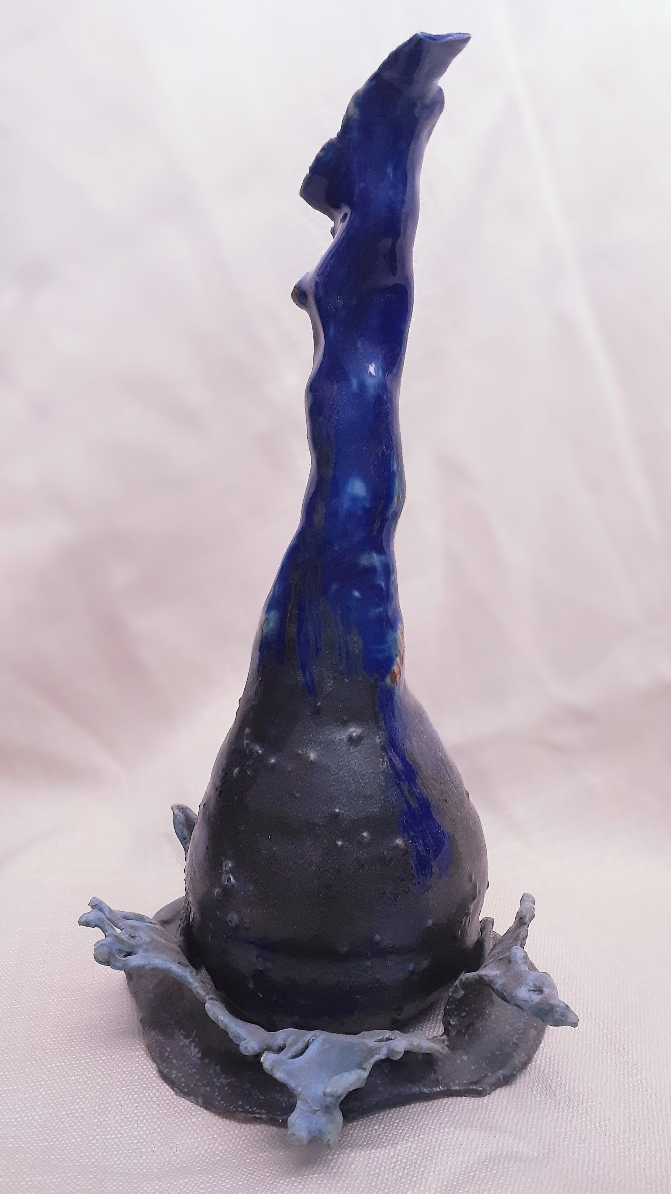 A blue ceramic vase in the shape of a falling water drop.
