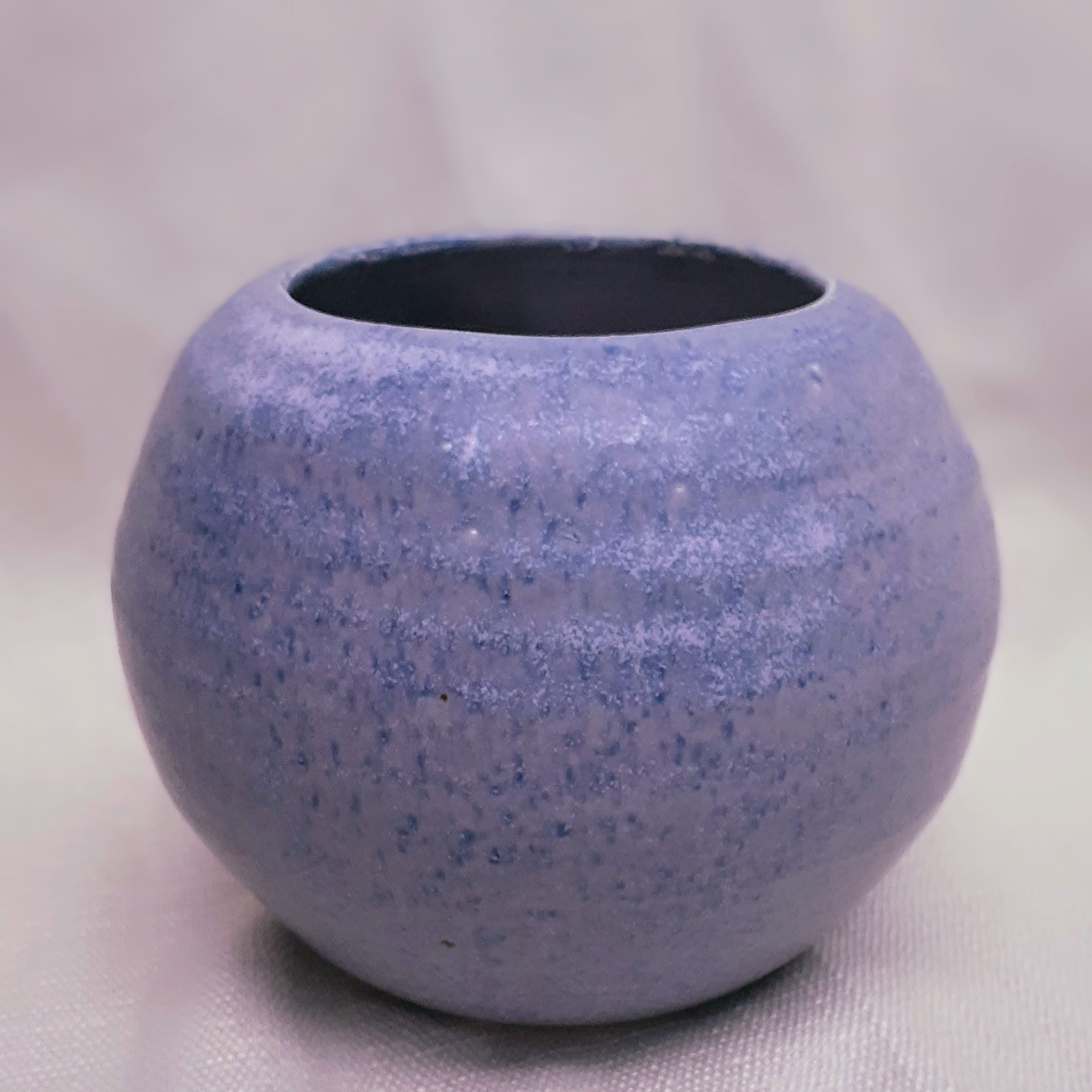 A round, purple, ceramic vessel